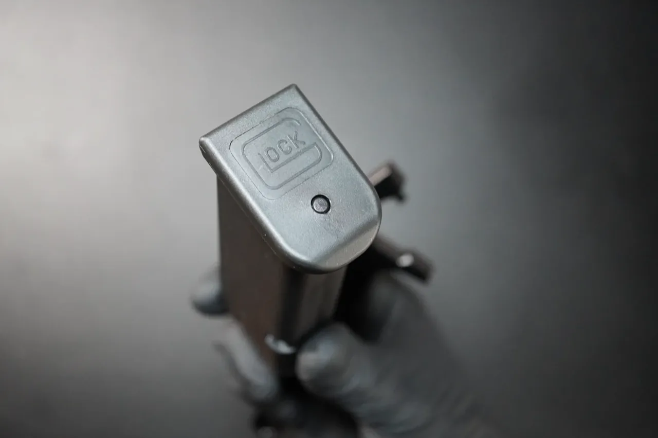 Bottom of an assembled Glock magazine showing the floor plate and access hole — start state